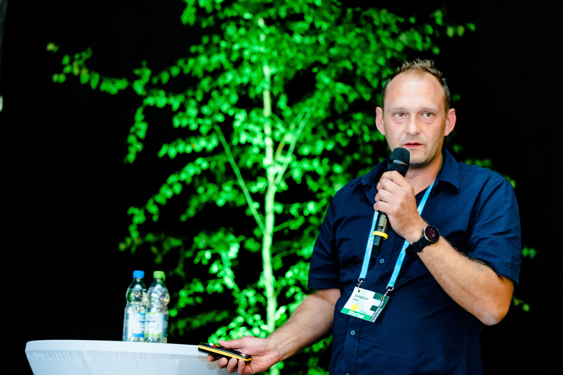 Sebastian Hinz speaking with a microphone on stage at the Future Forest Forum